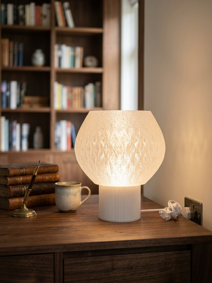 Lampada da tavolo stampata in 3D Sferonda accesa su un mobile in legno con libri e tazza, luce calda e diffusa – KreoLumo